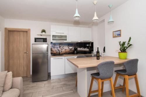 eine Küche mit weißen Schränken und einem Tisch und Stühlen in der Unterkunft Apartments Galic in Šibenik