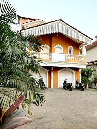 a house with a motorcycle parked in front of it at Reev's Homestay: Luxury 2 Bedroom apartment in Arossim-Cansaulim