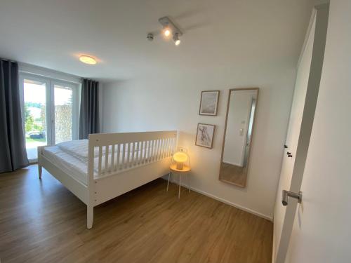 een witte slaapkamer met een wieg en een spiegel bij Apartment Kaapi in Friedrichshafen