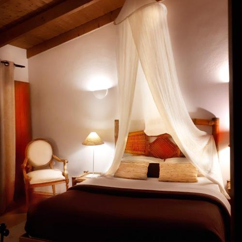 a bedroom with a canopy bed with a chair at SeteQuintas in Zambujeira do Mar