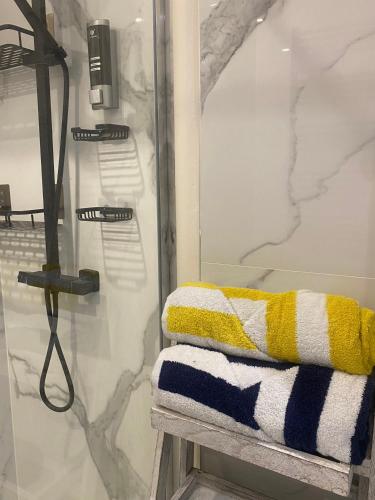 une douche avec une serviette jaune et bleue sur un banc dans l'établissement Centre Ville Sainte maxime 100M plage et commerce a pied, à Sainte-Maxime