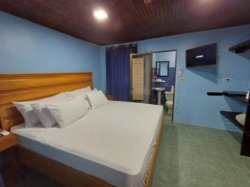 1 dormitorio con 1 cama blanca grande y pared azul en Pura Vida Aparment - Downtown La Fortuna, en Fortuna