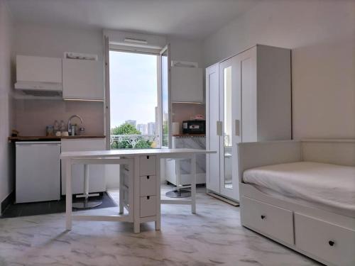 cocina blanca con escritorio y cama en Paris tourist Apartment, France, en Stains