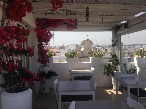 a balcony with flowers and tables and a view of a city at B&B Donnapasqua in Polignano a Mare