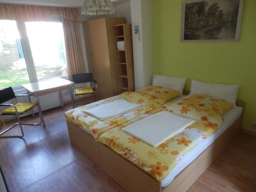 a bedroom with a bed and a table and a window at Bramkamp Pension in Dallgow