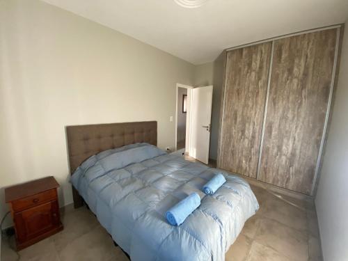 a bedroom with a large bed with blue pillows on it at Mendoza Deptos apart in Guaymallen