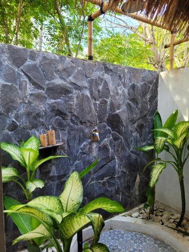 a bathroom with a stone wall and some plants at Gili Matiki in Gili Air