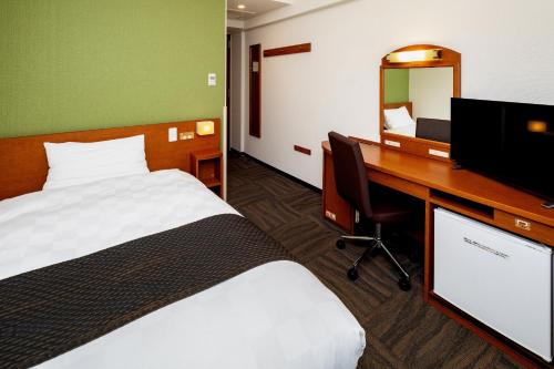 熊本市にある熊本東急REIホテルのベッド2台、デスク、コンピュータが備わるホテルルームです。