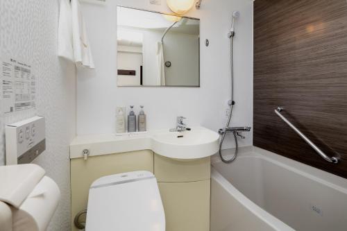 a bathroom with a sink and a toilet and a mirror at Kumamoto Tokyu REI Hotel in Kumamoto