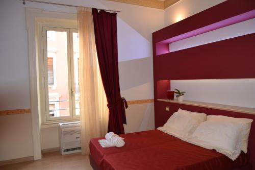 1 dormitorio con 1 cama con cabecero rojo y ventana en B&B The Queens, en Foggia
