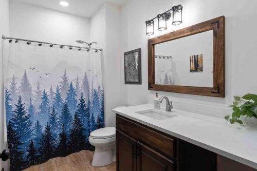 a bathroom with a toilet and a shower curtain with trees at Luxe Mt. Rainier Lodge w/ Hot Tub-AC-Game Room in Ashford