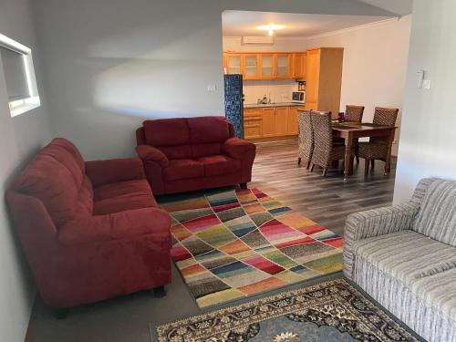 a living room with two chairs and a red couch at Central Shenton unit Outside Dog Friendly, near hospital in Geraldton