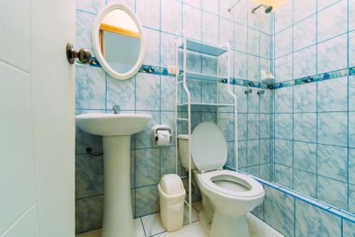 a blue tiled bathroom with a toilet and a mirror at Hospedaje Mary in Paracas