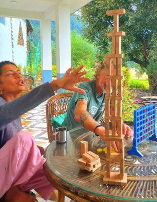 a woman helping a man play with a wooden tower at Riverside Homes in Deorāli