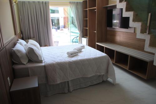 a bedroom with a bed with white sheets and a window at Star Palace Hotel Jeri in Jericoacoara