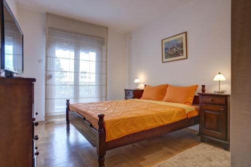 a bedroom with a bed with orange sheets and a window at Apartment Sahala in Tivat