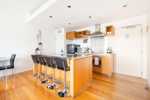 a kitchen with a counter with a bar with stools at The Landings Parnell in Auckland