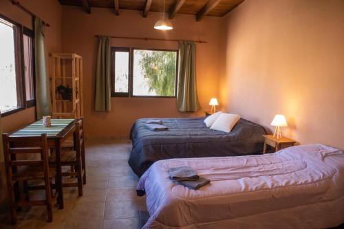 a room with two beds and a table and a desk at El Aromito Hospedaje in Tilcara