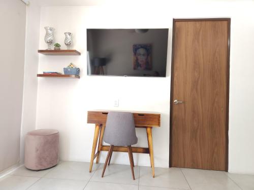 a desk with a chair and a television on a wall at Depa nuevo en el corazón de GDL con seguridad y alberca in Guadalajara