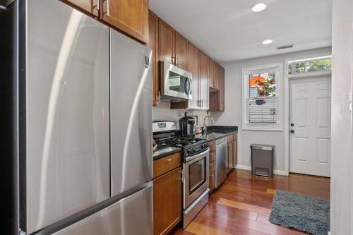 a kitchen with a stainless steel refrigerator and wooden cabinets at Perfect Location! Stylish Condo Steps Away from Nationals Stadium and Navy Yard in DC's Southwest Gem in Washington, D.C.