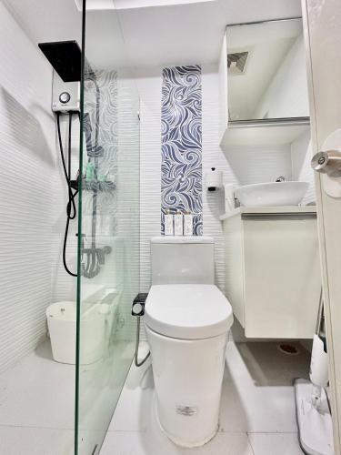 a white bathroom with a toilet and a shower at Queen Size Studio in Cebu City in Mandaue City