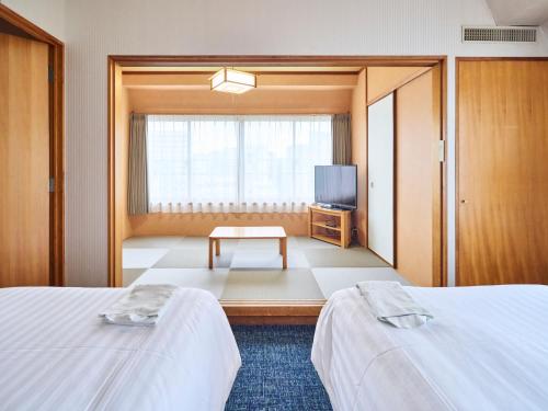 a hotel room with two beds and a television at Court Hotel Fukuoka Tenjin in Fukuoka