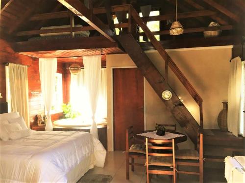 a bedroom with a bed and a table and a staircase at Cabana dos Sonhos na Serra SC in Rancho Queimado