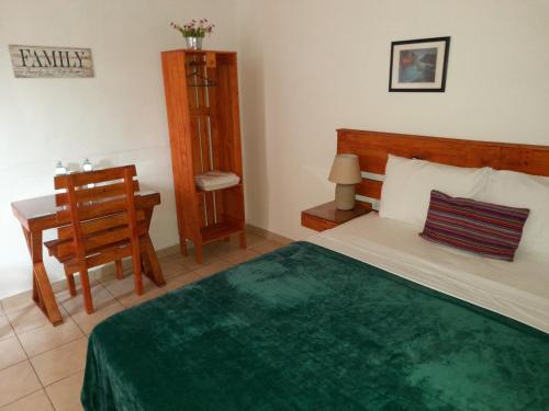 Hostal Puertas De Apaneca في Apaneca: غرفة نوم بسرير ومكتب وكرسي