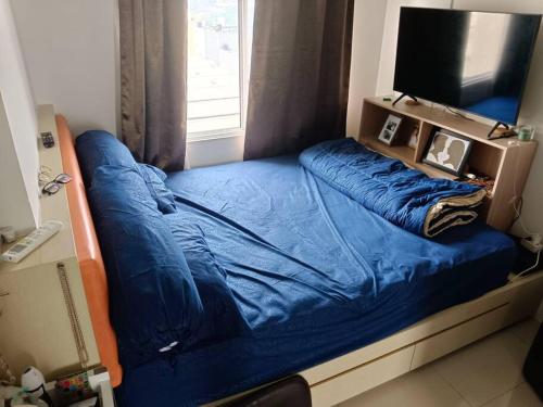 a bedroom with a blue bed with a window at busy city street in Cihuni