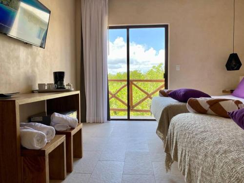 1 dormitorio con 2 camas y vistas a un balcón en sunsteps purple room en Holbox Island