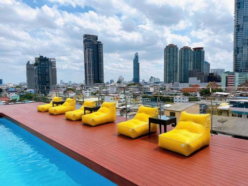 een rij gele stoelen en tafels op het dak van een gebouw bij Miloft Sathorn Hotel - SHA Plus Certified in Bangkok
