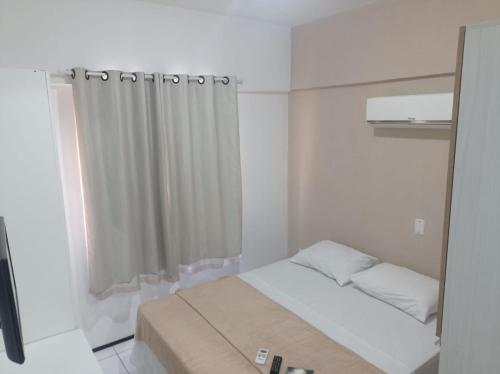 a small white room with a bed and a shower at Brisa Brasil Residence in Fortaleza