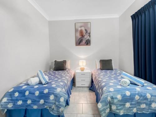 2 Einzelbetten in einem Zimmer mit blauen Vorhängen in der Unterkunft Arcadia Beach Unit 1 in Arcadia