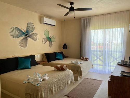 a bedroom with two beds and a ceiling fan at sunsteps dragonfly room in Holbox Island