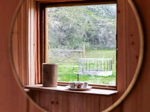 a mirror reflecting a window with a view of a field at Falgate Shepherds Hut in Caston