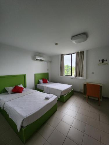 een kamer met 2 bedden en een raam erin bij Y Hotel in Kota Kinabalu