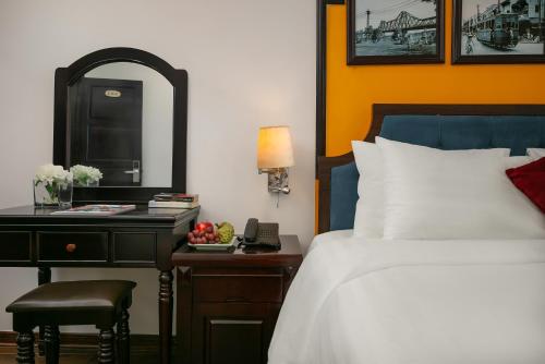 a bedroom with a bed and a desk with a mirror at Silk Castle Hotel & Spa - Hanoi Old quarter in Hanoi