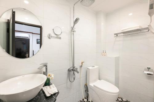 ein weißes Badezimmer mit einem Waschbecken und einem Spiegel in der Unterkunft Silk Castle Hotel & Spa in Hanoi