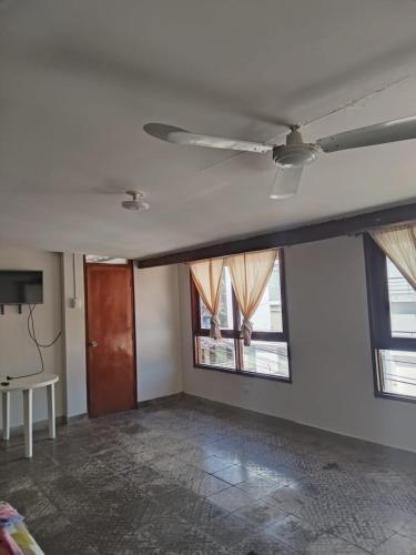 a living room with a ceiling fan and two windows at Piura Eterno Calor in Piura