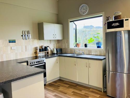 uma cozinha com um frigorífico de aço inoxidável e uma janela em Perma Ridge Farmstay em Ngaruawahia