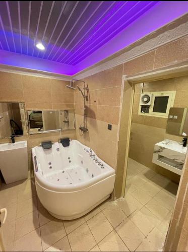 a large tub in a bathroom with a purple ceiling at Al Muftaha Apartment in Abha