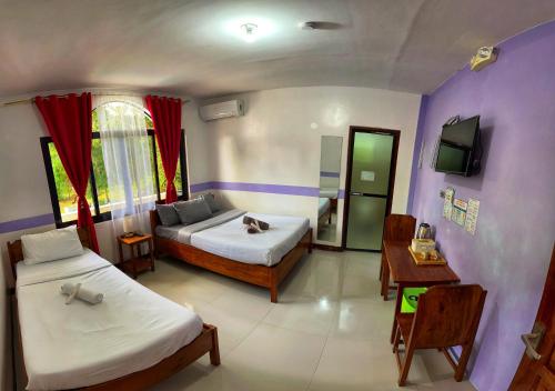 a bedroom with two beds and a tv in it at White Summerville Tourist Inn in Busuanga