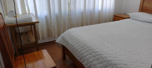 ein Schlafzimmer mit einem Bett und einem Tisch und einem Fenster in der Unterkunft HOSPEDAJE GIMAJA in Villa Rica