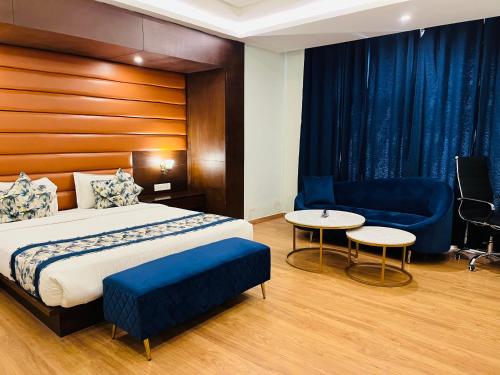 a bedroom with a bed and a couch and a table at Hotel Myriad in Lucknow