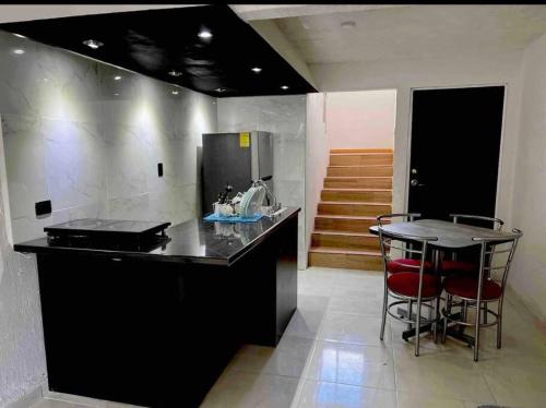 une cuisine avec un comptoir noir et un bar avec des tabourets dans l'établissement 1 casa cochera 2 recamaras centrica, à Torreón
