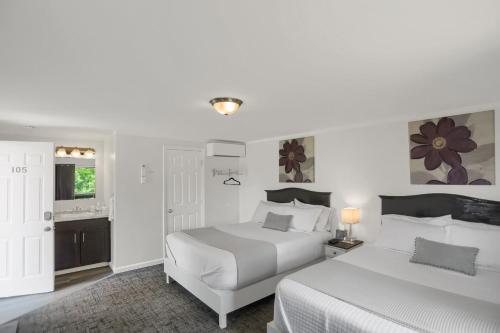 a white bedroom with two beds and a bathroom at Halifax Inn in Halifax