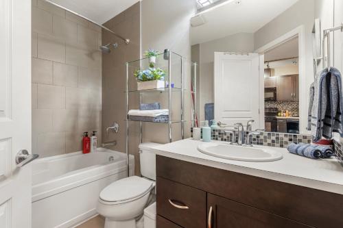 a bathroom with a sink and a toilet and a bath tub at City Centre Retreat - 1BR Condo with Desk in Calgary