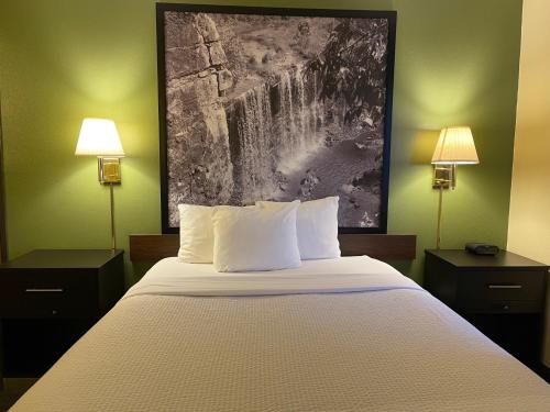 a bedroom with a bed with two lamps and a painting on the wall at Super 8 by Wyndham Colby in Colby