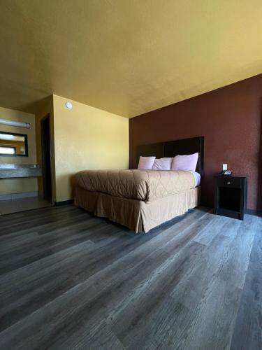 1 dormitorio con 1 cama y suelo de madera en Budget Inn of Ada, en Ada