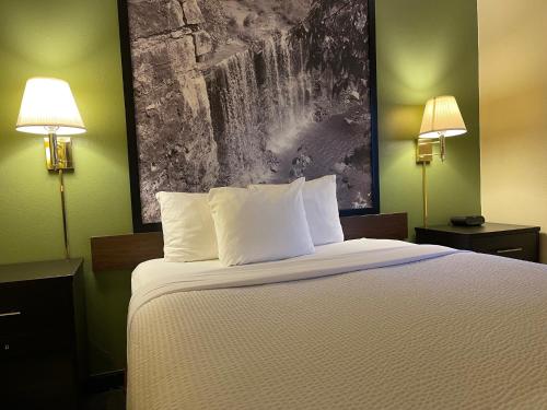 a bedroom with a bed with two lamps and a painting on the wall at Super 8 by Wyndham Colby in Colby